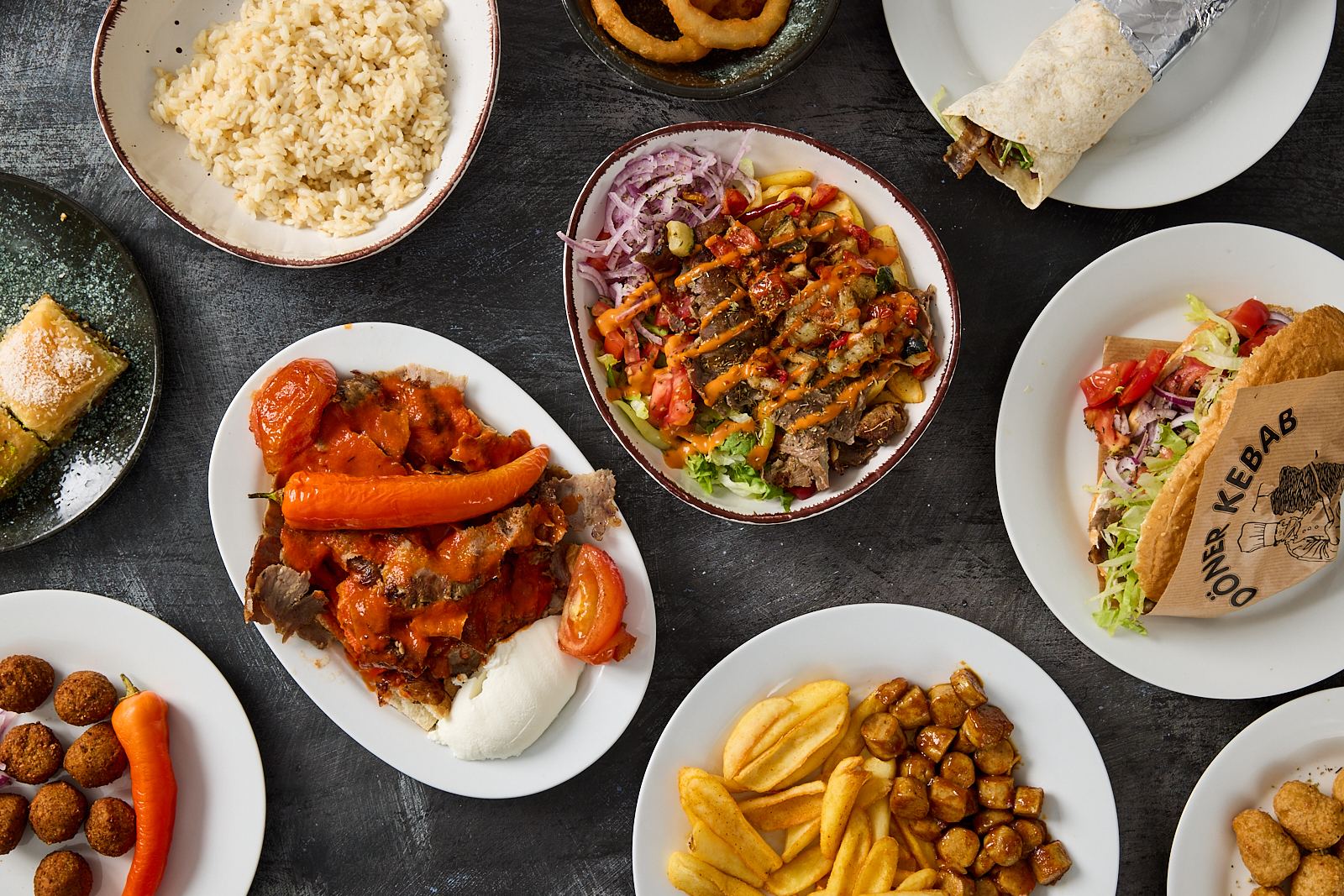 Ausgewählte Gerichte von Moe's Kebap von oben fotografiert: Döner, İskender, Dürüm, Falafel, Currywurst und Baklava